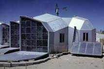 Un esempio di una casa a energia solare. Un mulino a vento pompa l’acqua e pannelli solari riscaldano gli ambienti interni.